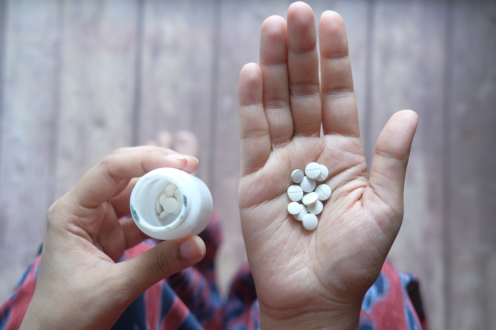 A person holding several Tramadol pills and the bottle in their hand