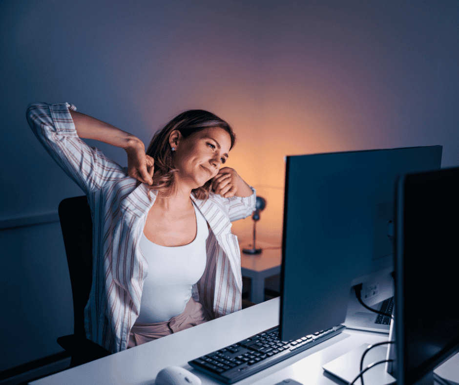 young blonde woman stretching at her desk due to her posture and back pain
