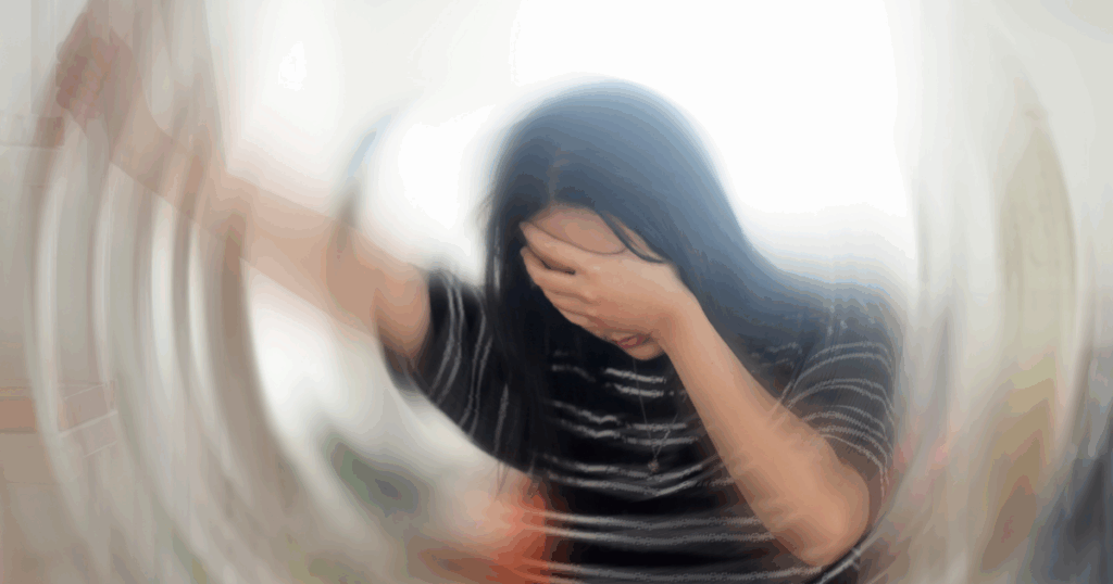 young woman with dark hair holding her head with the room spinning due dizziness and vertigo